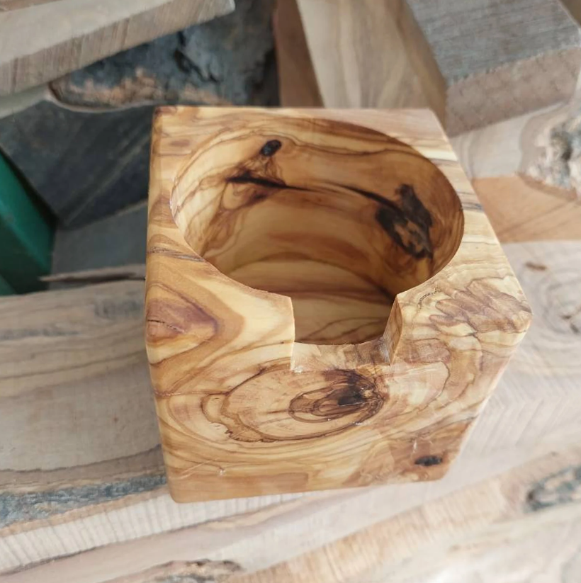 A wooden stand made of olive wood, designed to hold a Gaggia portafilter, displayed on a wooden surface.