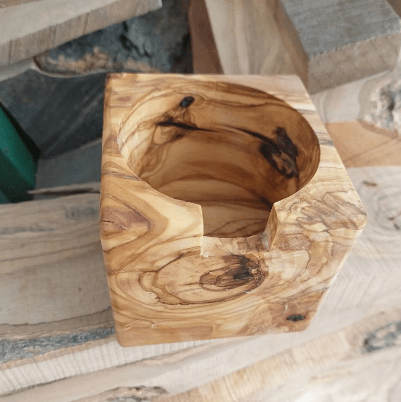 A wooden stand made of olive wood, designed to hold a Gaggia portafilter, displayed on a wooden surface.