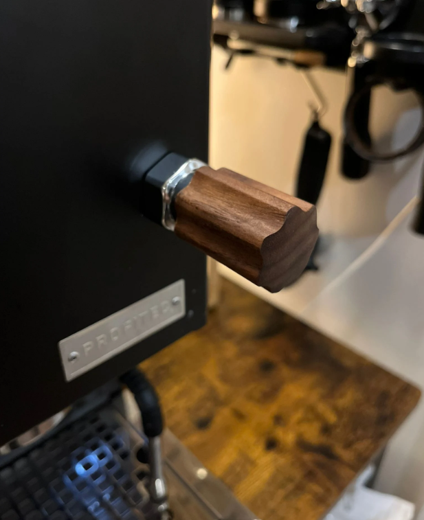 A wooden knob attached to a black Profitec Go coffee machine, designed to adjust the grind size.